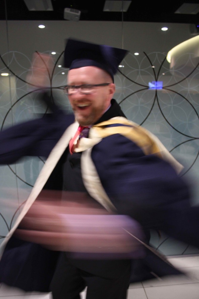Man in academic dress spins